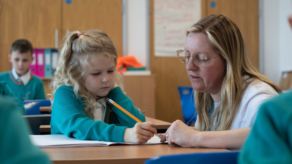 A teacher helping a young child to write